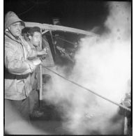 Au cours d'une mission de dragage de nuit, des marins remontent ou larguent une drague avec un treuil à vapeur à bord d'un chalutier réquisitionné par la Marine nationale pour servir de dragueur de mines.