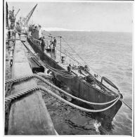 Le sous-marin des Forces navales françaises libres la Minerve est accosté à quai par tribord dans un port.