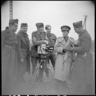 Un caméraman anglais s'appuie sur sa caméra, il est entouré de soldats.