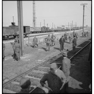 En gare de Trappes plan général d'une voie ferrée près de laquelle des soldats debout attendent.