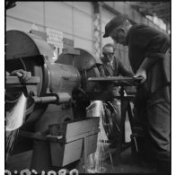 A l'atelier d'Issy-les-Moulineaux des ouvriers passent à la meuleuse une pièce métallique.