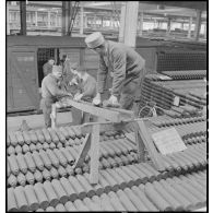 Des ouvriers chargent des obus dans un wagon de chemin de fer.