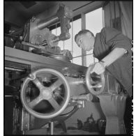 En atelier un apprenti de la cartoucherie de Vincennes travaille sur une machine-outil.