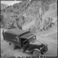 Le camion du SCA est photographié en plan général de trois quarts avant en plongée sur une route de montagne.