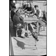 Des légionnaires du 1er REI mangent sur une table à l'extérieur.
