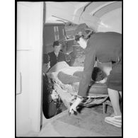 Transport d'un blessé à bord d'un avion sanitaire avec l'aide des infirmières de l'air.