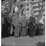 Louis Jacquinot, ministre aux anciens combattant, portant un drapeau lors d'une visite au monument aux morts d'Alger.