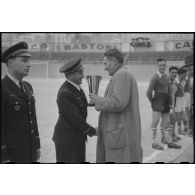 Remise de coupe à un militaire par une autorité civile au stade d'Alger lors d'un championnat militaire.