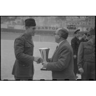 Remise de coupe par une autorité civile à un militaire lors de la finale d'un championnat militaire à Alger.