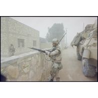 Dans une rue d'Al Salman, un tireur d'élite du 3e RIMa (régiment d'infanterie de marine), son fusil de précision FR-F2 en main, se tient debout derrière un muret.