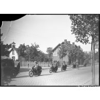 Des motards britanniques de la BEF se déplacent en colonne dans un village minier du département du Nord.