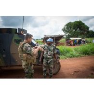 Debout à côté d'un PVP (petit véhicule protégé), le capitaine de la compagnie bleue du GTIA (groupement tactique interarmes) Vercors s'entretient avec son homologue des casques bleus congolais de la MINUSCA (mission multidimensionnelle intégrée des Nations Unies pour la stabilisation en Centrafrique), lors d'une patrouille dans la ville de Boda à 200 Km au nord-ouest de Bangui.