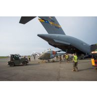 Chargement d'un hélicoptère de reconnaissance Fennec AS-555 AN du DETFENNEC (détachement Fennec) dans la soute d'un avion cargo C-17 de l'US Air Force par un tracteur industriel et d'aéroport Tracma, dans le cadre de son désengagement depuis le camp M'Poko de Bangui.