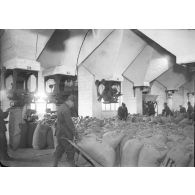 Sous des silos à grains des soldast manipulent des sacs de farine.