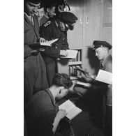 A bord d'un sous-marin allemand, des marins allemands parcourent des ouvrages pour illustrer la semaine du livre allemand.