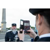 Une élève de l'école de gendarmerie prend un gendarme en photographie avec son téléphone avant le défilé à pied du 14 juillet sur la place de la Concorde.