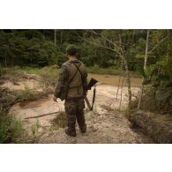 Un chef de groupe du 3e régiment étranger d'infanterie (3e REI) patrouille armé d'un fusil à pompe Mossberg 500 sur un site d'orpaillage à Ouanary, en Guyane française.