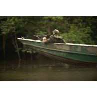 Un stagiaire patrouille à bord d'une pirogue armé de sa mitrailleuse FN Minimi sur le fleuve Approuague à Régina, en Guyane française.