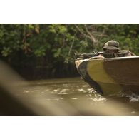 Un stagiaire patrouille à bord d'une pirogue armé de sa mitrailleuse FN Minimi sur le fleuve Approuague à Régina, en Guyane française.