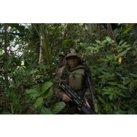 Un stagiaire patrouille armé de sa mitrailleuse FN Minimi au centre d'entraînement en forêt équatoriale (CEFE) à Régina, en Guyane française.