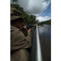 Un stagiaire patrouille à bord d'une pirogue armé d'une mitrailleuse FN Minimi sur le fleuve Approuague à Régina, en Guyane française.