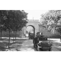 Colonne de véhicules militaires passant sous une porte de ville en mai 1945.