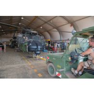 Des mécaniciens remorquent un hélicoptère Caiman NH-90 au moyen d'un tracteur Tracma TD 1500 pour sa sortie de hangar à Gao, au Mali.