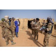 Des soldats maliens font un don de matériel scolaire auprès d'un professeur d'une école de la région d'Ansongo, au Mali.