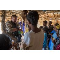 Un chef de section du détachement de liaison et d'appui opérationnel n°3 (DLAO) distribue des pâtes de fruit à des élèves d'une école de la région d'Ansongo, au Mali.