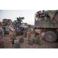 Des soldats du 35e régiment d'infanteire (RI) remplissent leurs jerricans de carburant à l'arrière d'un camion GBC-180 lors d'un bivouac dans la région d'Ansongo, au Mali.