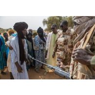 Des soldats maliens contrôlent des habitants pour une consultation médicale au centre de santé communautaire (CESCOM) de Tamkoutat, au Mali.