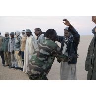 Un soldat nigérien fouille des orpailleurs interceptés sur la piste transsaharienne au Niger.