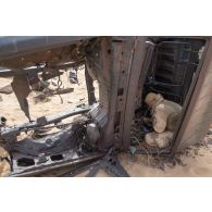 Un élément opérationnel de déminage (EOD) fouille l'intérieur d'une épave de véhicule sur une zone minée au Niger.