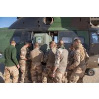 Des soldats du 1er régiment de chasseurs (RCh) déchargent une boîte de vitesse pour véhicule léger de reconnaissance et d'appui (VLRA) depuis un hélicoptère Puma SA-330B sur l'axe Berliet, au Niger.