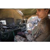 Un transmetteur communique en code morse à bord d'un véhicule léger de reconnaissance et d'appui (VLRA) un moyen d’élongation pour les communications hautes fréquences interarmées et OTAN en réseau (MELCHIOR) sur l'axe Berliet, au Niger.