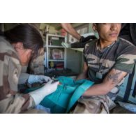 Une infirmière recoud le doigt d'un soldat à bord d'un véhicule léger de reconnaissance et d'appui (VLRA) sanitaire (SAN) sur l'axe Berliet, au Niger.