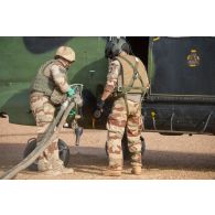 Un logisticien du Service des essences des armées (SEA) ravitaille un hélicoptère Puma SA-330B auprès d'un membre opérationnel de soute (MOS) sur l'axe Berliet, au Niger.