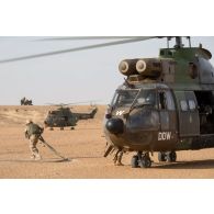 Des logisticiens du Service des essences des armées (SEA) ravitaillent un hélicoptère Puma SA-330B en carburant sur l'axe Berliet, au Niger.