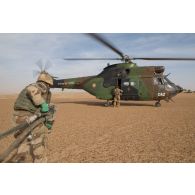 Un logisticien du Service des essences des armées (SEA) ravitaille un hélicoptère Puma SA-330B en carburant sur l'axe Berliet, au Niger.