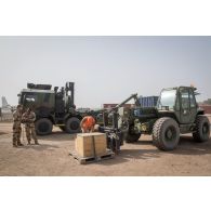 Des logisticiens chargent des caisses de matériel au moyen d'un chariot Manitou en zone logistique de la base aérienne de N'Djamena, au Tchad.
