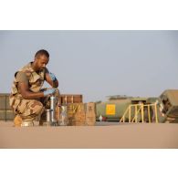 Le brigadier-chef Julien, conducteur-ravitailleur, prélève des échantillons de carburant depuis un bac souple pour les analyser au laboratoire du site d'exploitation du Service des essences des armées (SEA) à Niamey, au Niger.