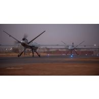 Roulage d'un drone General Atomics MQ-9 Reaper vers son hangar à la tombée de la nuit à Niamey, au Niger.