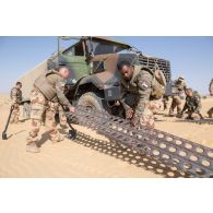 Des soldats déploient des plaques PSP pour désensabler un camion-citerne CBH-385 du Service des essences des armées (SEA) sur l'axe Berliet, au Niger.