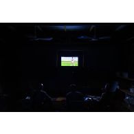 Des soldats regardent la retransmission d'un match de football à la télévision en zone vie du camp de Gao, au Mali.