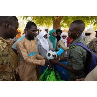 Un soldat malien distribue des ballons de football à des habitants d'Andéramboukane, à la frontière avec le Niger.