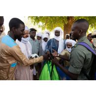 Un soldat malien distribue des ballons de football à des habitants d'Andéramboukane, à la frontière avec le Niger.