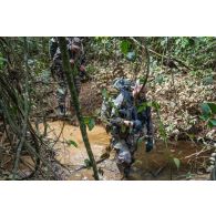Des soldats du 7e bataillon de chasseurs alpins (BCA) franchissent un marécage en forêt à Maripasoula, en Guyane française.