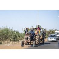 Des agriculteurs progressent à bord d'un tracteur en bordure de route à Bamako, au Mali.