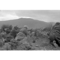 Un groupe de soldats est allongé au sommet d'une colline, tir d'une mitrailleuse MG-34.