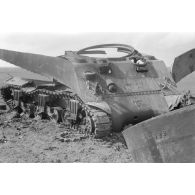 Un Leutnant et deux hommes examinent la carcasse déchiquetée d'un char Sherman M4 .